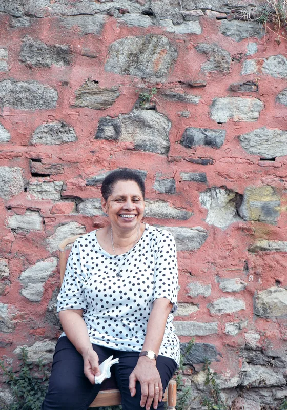 Woman laughing against a stone wall